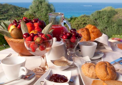 een tafel vol fruit en een schaal met eten bij Punta Falcone Resort in Santa Teresa Gallura