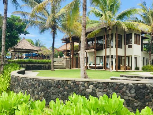 a resort with palm trees and a stone wall at Anapuri Villas in Ketewel
