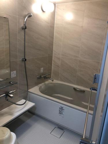 a bathroom with a tub and a shower and a toilet at Nishikawaguchi Station Hotel Stay Lounge in Kawaguchi