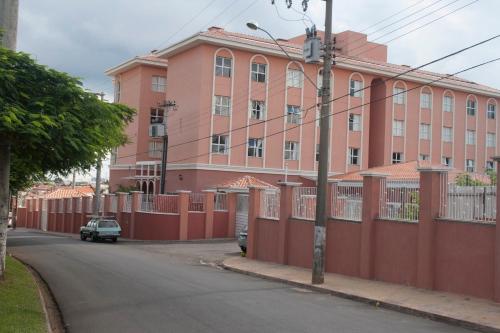 a pink building with a red fence next to a street at The Hill Hotéis Executive in São Carlos