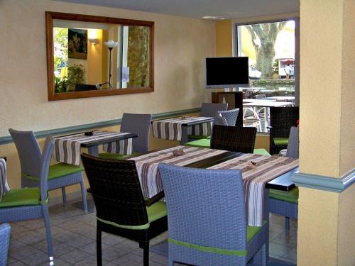 a restaurant with tables and chairs and a mirror at Logis Hotel De L'Etang in Cucuron