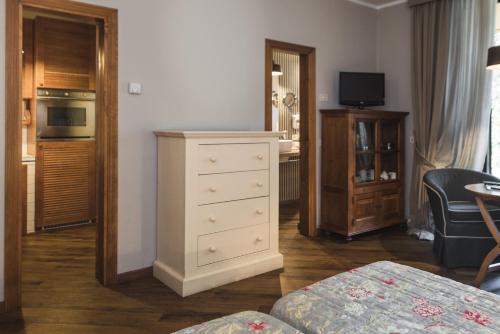 a living room with a white dresser and a kitchen at Roccamare Resort - Ville e Appartamenti in Castiglione della Pescaia