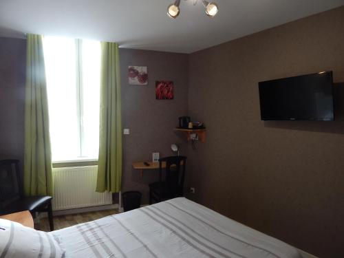 a bedroom with a bed and a television on the wall at Le Lion D'or in Ouroux en Morvan