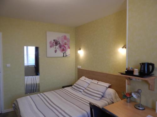 a bedroom with a bed and a table and a mirror at Le Lion D'or in Ouroux en Morvan