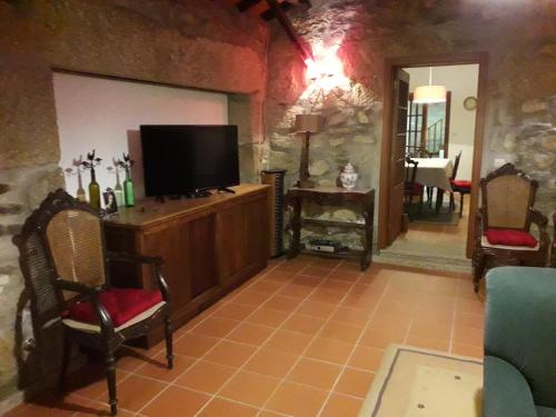 a living room with a flat screen tv on a cabinet at Casa da Farmácia in Castanheiro
