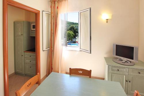 a dining room with a table and a television and a window at Il Villaggio Di Giuele in Finale Ligure