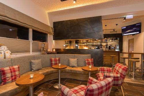 ein Restaurant mit Tischen und Stühlen und eine Bar in der Unterkunft Hotel Almrausch in Saalbach-Hinterglemm