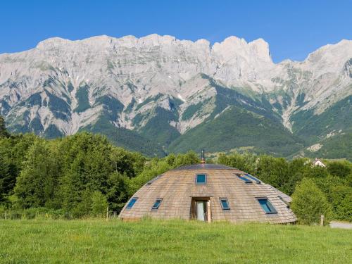 um grande edifício cúpula num campo com montanhas ao fundo em Au-Dela des Nuages, Maison d'hôtes insolite & SPA em Chauffayer