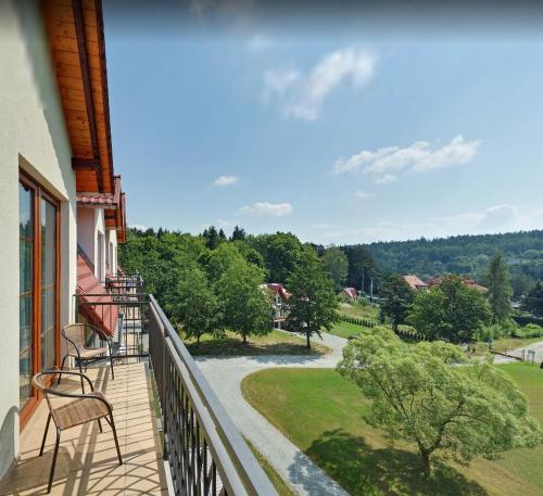 a balcony with chairs and a view of a park at Hotel Nowy Zdrój - Centrum Zdrowia i Wypoczynku in Polanica-Zdrój