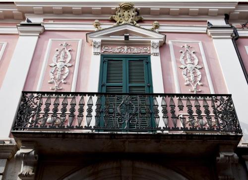 a balcony with a green window on a pink building at La Casa nel Borgo Antico in Melfi