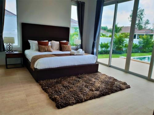 a bedroom with a large bed with a large window at Villa de Veluwe @ Hua Hin in Hua Hin