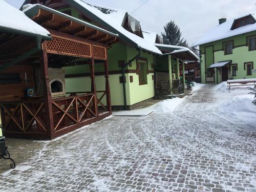 a cobblestone street in front of a building with snow at Emerald House in Mykulychyn
