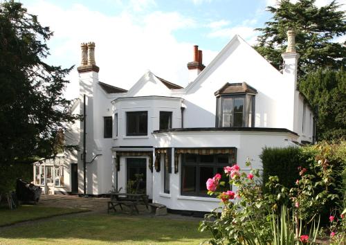 uma casa branca com flores no quintal em West End Lodge em Esher