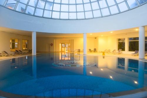 a large swimming pool in a building with a glass ceiling at Royal Tulip Taj Sultan in Hammamet