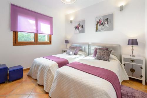 two beds in a room with white and purple at Serena Villa in Ibiza Town