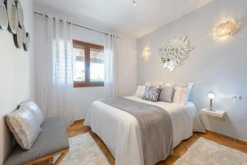a white bedroom with a bed and a window at Serena Villa in Ibiza Town