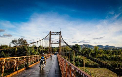 two people riding bikes on a bridge at Kontum Home Sweet Homestay in Kon Tum