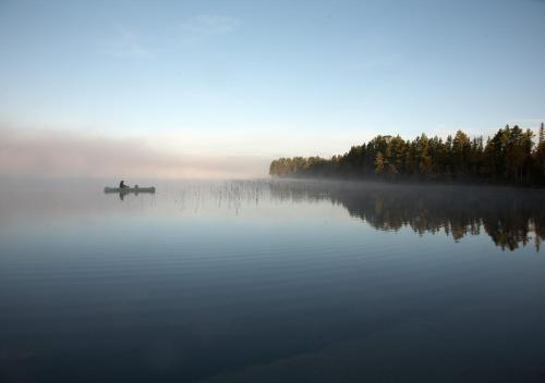 a person in a boat on a misty lake at Sara´s Bed and Breakfast in Erikslund