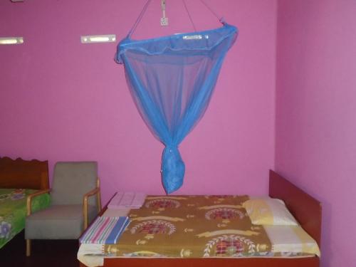 a bedroom with a bed and a blue curtain at El Shaddai in Mannar
