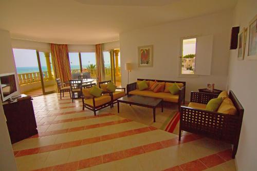 een woonkamer met een bank, stoelen en een tafel bij Golden Tulip Taj Sultan Resort in Hammamet