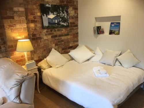 a bedroom with a bed and a lamp and a brick wall at Gorgeous studio 2 minutes from the heart of Subiaco in Perth