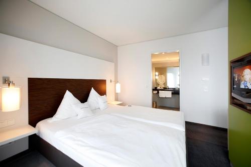 a bedroom with a white bed and a television at SportHotel Kaiserau in Kamen