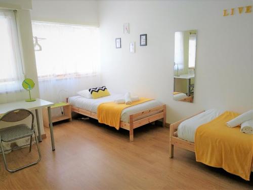 a bedroom with two beds and a desk and a mirror at D Wan Guest House in Peniche