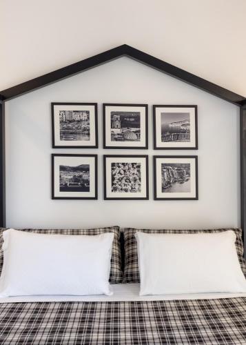 a white wall with pictures above a bed with pillows at Maison Bon Bon in Sorrento