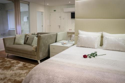 a bedroom with a large bed with a couch and roses on it at Quinta dos Jasmins in Paços de Ferreira
