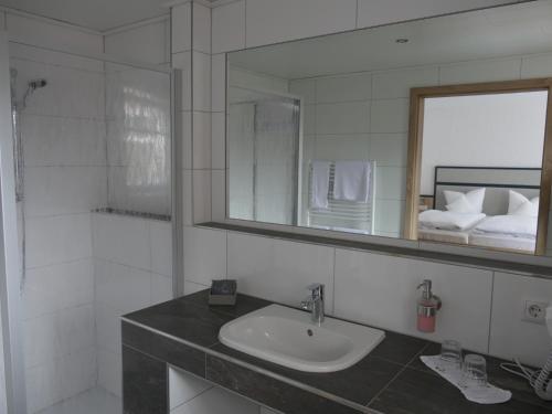 La salle de bains est pourvue d'un lavabo et d'un miroir. dans l'établissement Hotel Diekgerdes, Komfortzimmer, à Cloppenburg