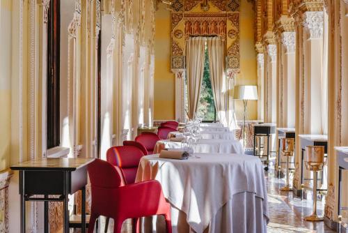 a row of tables in a room with red chairs at Relais & Chateaux Villa Crespi in Orta San Giulio