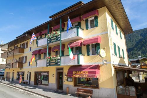 a yellow building with flags on it on a street at Albergo Garni Barancio in Auronzo di Cadore