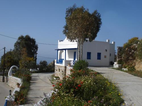 a white house with a tree on the side of a road at Blue Horizon Ios in Ios Chora