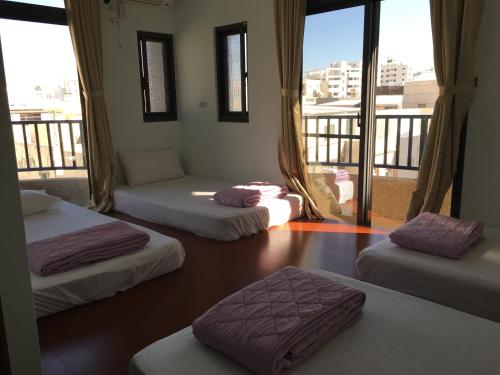 a room with three beds and a balcony with windows at Guang Cyuan homestay in Magong