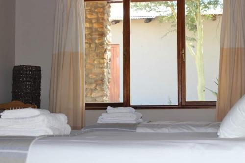 Schlafzimmer mit einem Bett mit weißer Bettwäsche und einem Fenster in der Unterkunft Ribboksfontein Guest Farm in De Rust