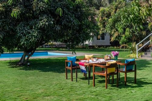 a table and chairs in the grass next to a pool at SaffronStays Casa Manga, Karjat - pet-friendly pool villa near ND's Film World and Saltt in Karjat