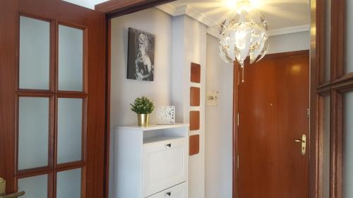 a hallway with a door and a chandelier at Apartamento frente a Palacio de Congresos (Fibes) in Seville