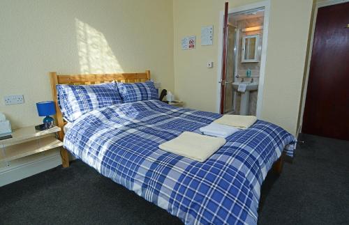 a blue and white bed with two towels on it at Lynmoore Guest House in Blackpool