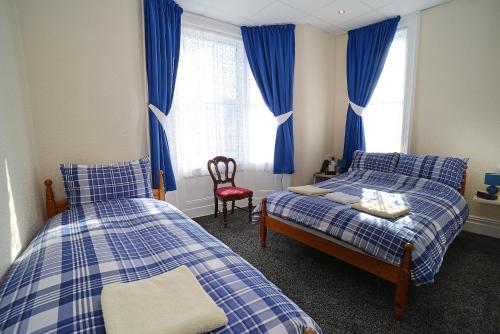 a bedroom with two beds and a chair and a window at Lynmoore Guest House in Blackpool