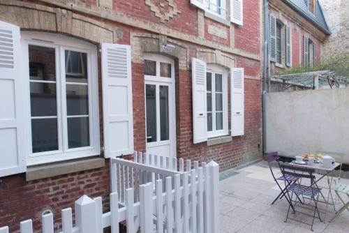 einen weißen Zaun vor einem Backsteingebäude in der Unterkunft Villa Arthur in Deauville