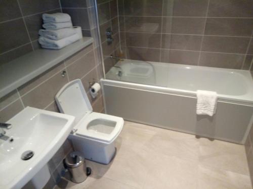 a bathroom with a sink and a toilet and a bath tub at Quay Apartments in Manchester