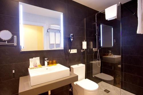 a bathroom with a sink and a toilet and a mirror at Hotel Pompaelo Plaza del Ayuntamiento & Spa in Pamplona