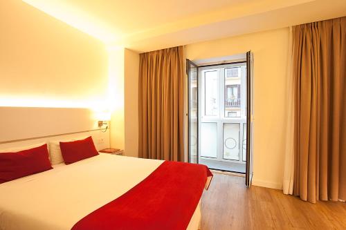 a hotel room with a bed and a large window at Hotel Pompaelo Plaza del Ayuntamiento & Spa in Pamplona