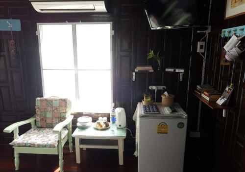 Habitación con mesa, nevera y silla. en Sichang My home, en Koh Sichang