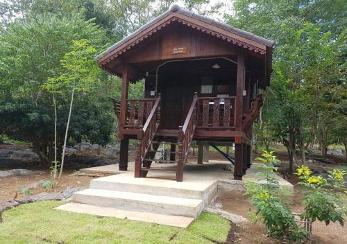 a small wooden gazebo with stairs in a garden at Sichang My home in Ko Si Chang