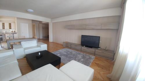 a living room with white furniture and a flat screen tv at Cross Resort Hotel in Yerevan