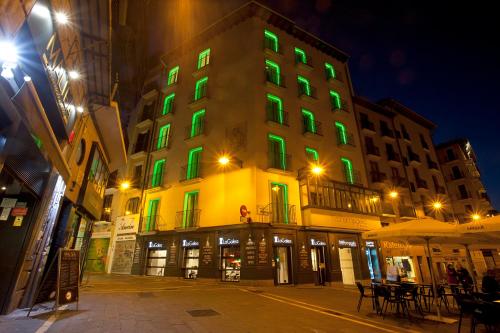 a building with green lights on it at night at Hotel Pompaelo Plaza del Ayuntamiento & Spa in Pamplona