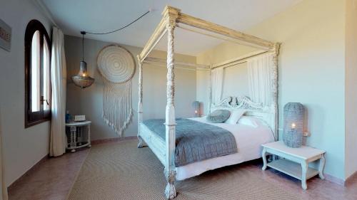- une chambre avec un lit à baldaquin blanc et une table dans l'établissement Mas Boronat Resort, à Salomó