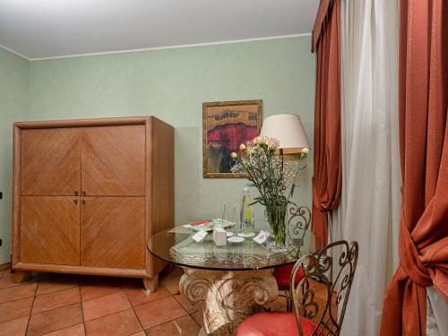 a room with a table with flowers and a cabinet at Active Hotel Paradiso in Peschiera del Garda