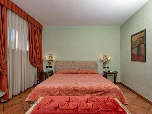 a bedroom with a bed with red sheets and two tables at Active Hotel Paradiso in Peschiera del Garda